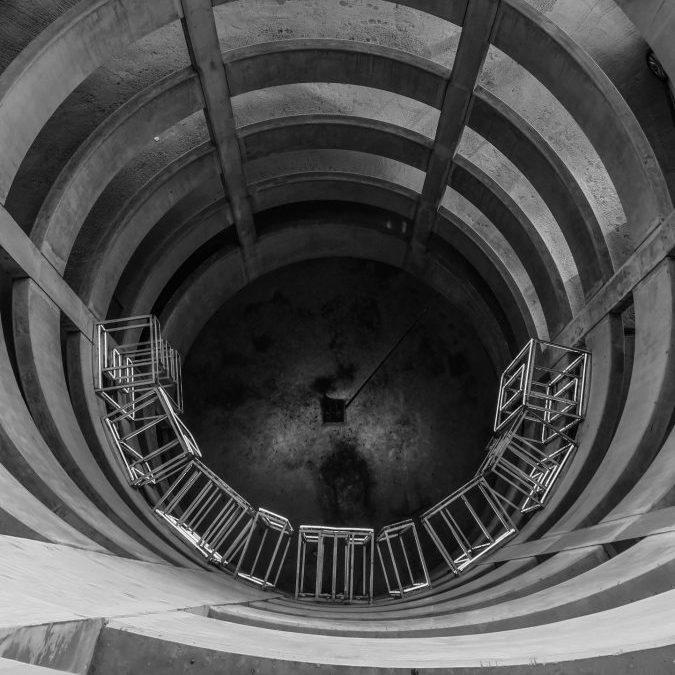 Dramatic black and white view of a spiral staircase inside a cylindrical architectural structure.