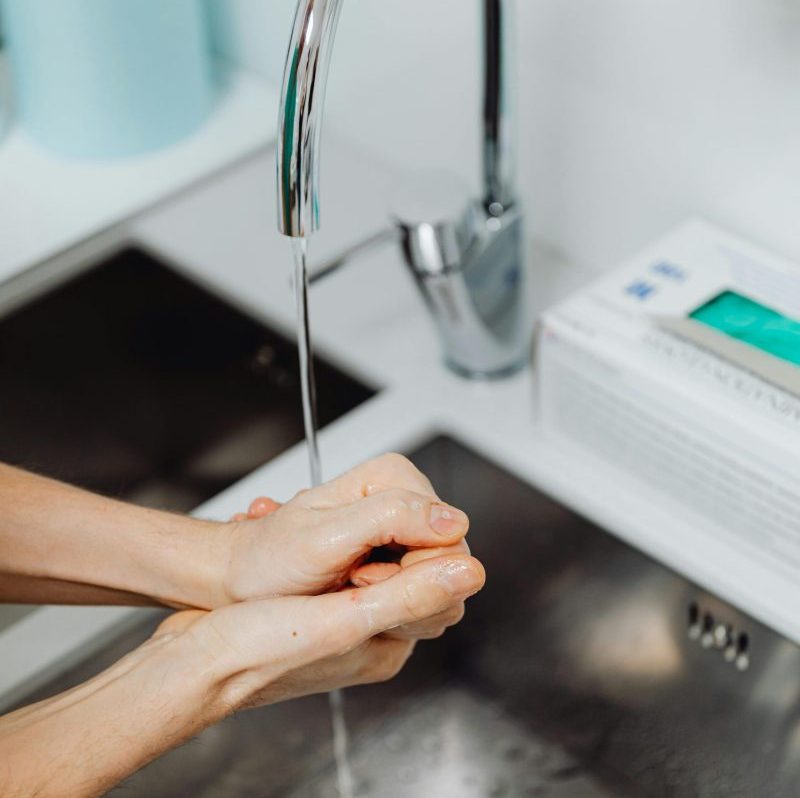 Hands being washed under a modern faucet, emphasizing hygiene and cleanliness.